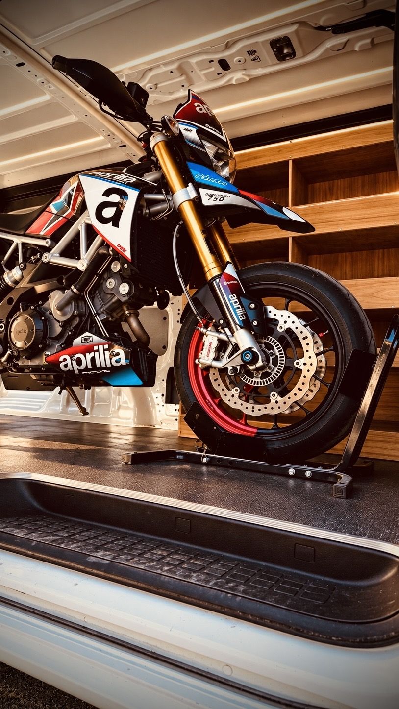 Moto sanglée dans une cale-roue à l'intérieur d'un utilitaire fermé
